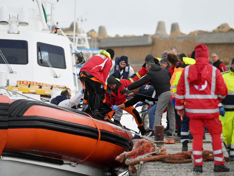  Italian Coast Guard officier carry the body of a deceased migrant in a bag, on February 27, 2023 in the port of Isola di Capo Rizzuto, south of Crotone, after a migrants' boat sank off Italy's southern Calabria region. - At least 59 migrants, including 11 children and a newborn baby, died after their overloaded boat sank early on February 26, 2023 in stormy seas off Italy's southern Calabria region, officials said. (Photo by Alessandro SERRANO / AFP)