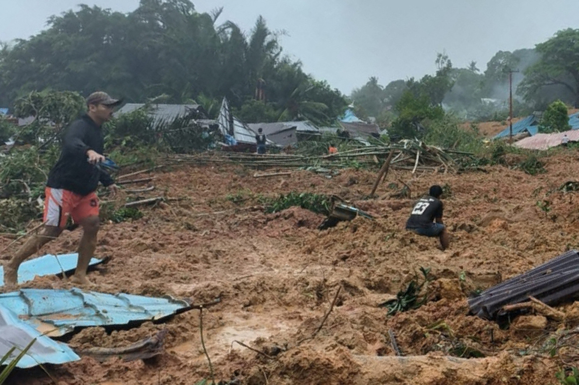  This handout photo taken and released on March 6, 2023 by the BNPB (National Disaster Management Agency) shows people inspecting the damage at a village that was hit by landslides in Natuna in Indonesia's Riau Province. - Eleven people were killed and dozens were missing after torrential rains and landslides battered one of Indonesia's outermost islands, the country's disaster agency said. (Photo by Handout / BNPB / AFP) / RESTRICTED TO EDITORIAL USE - MANDATORY CREDIT 