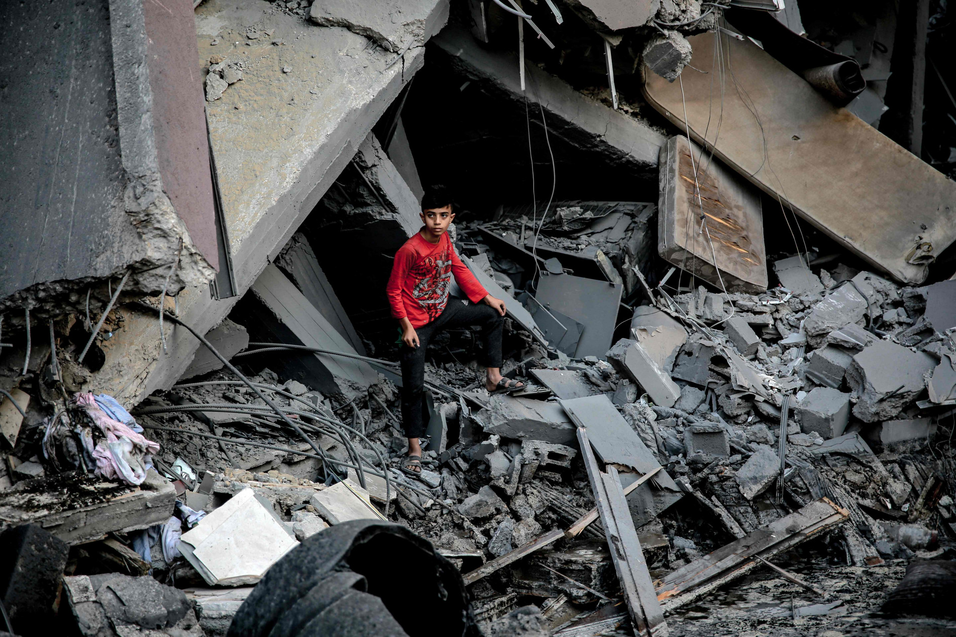 Jovem é visto entre escombros de um edifício em Gaza 