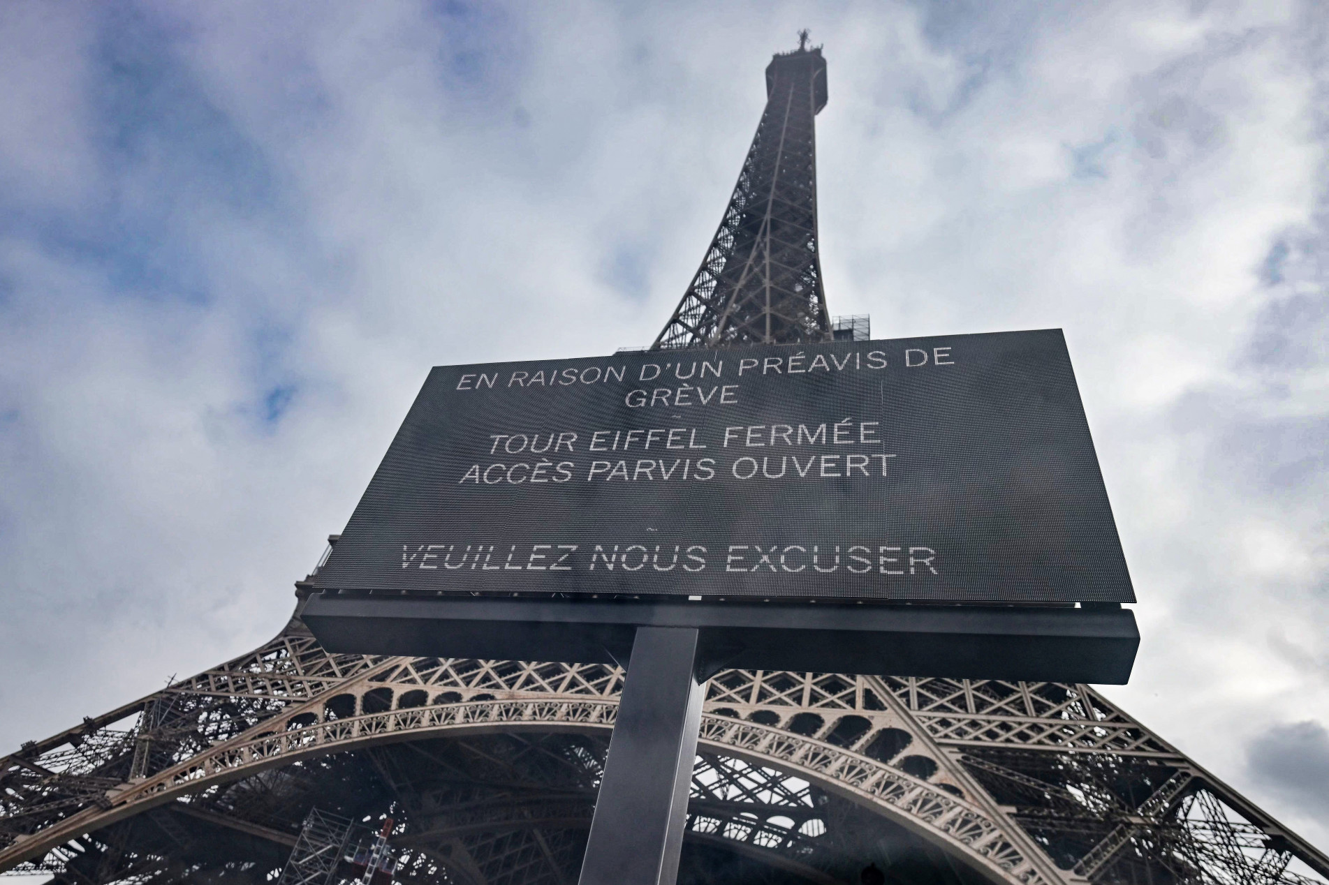 Um painel informa que, devido à greve, a Torre Eiffel está fechada, mas o parque continua aberto. Mensagem também pede desculpas 