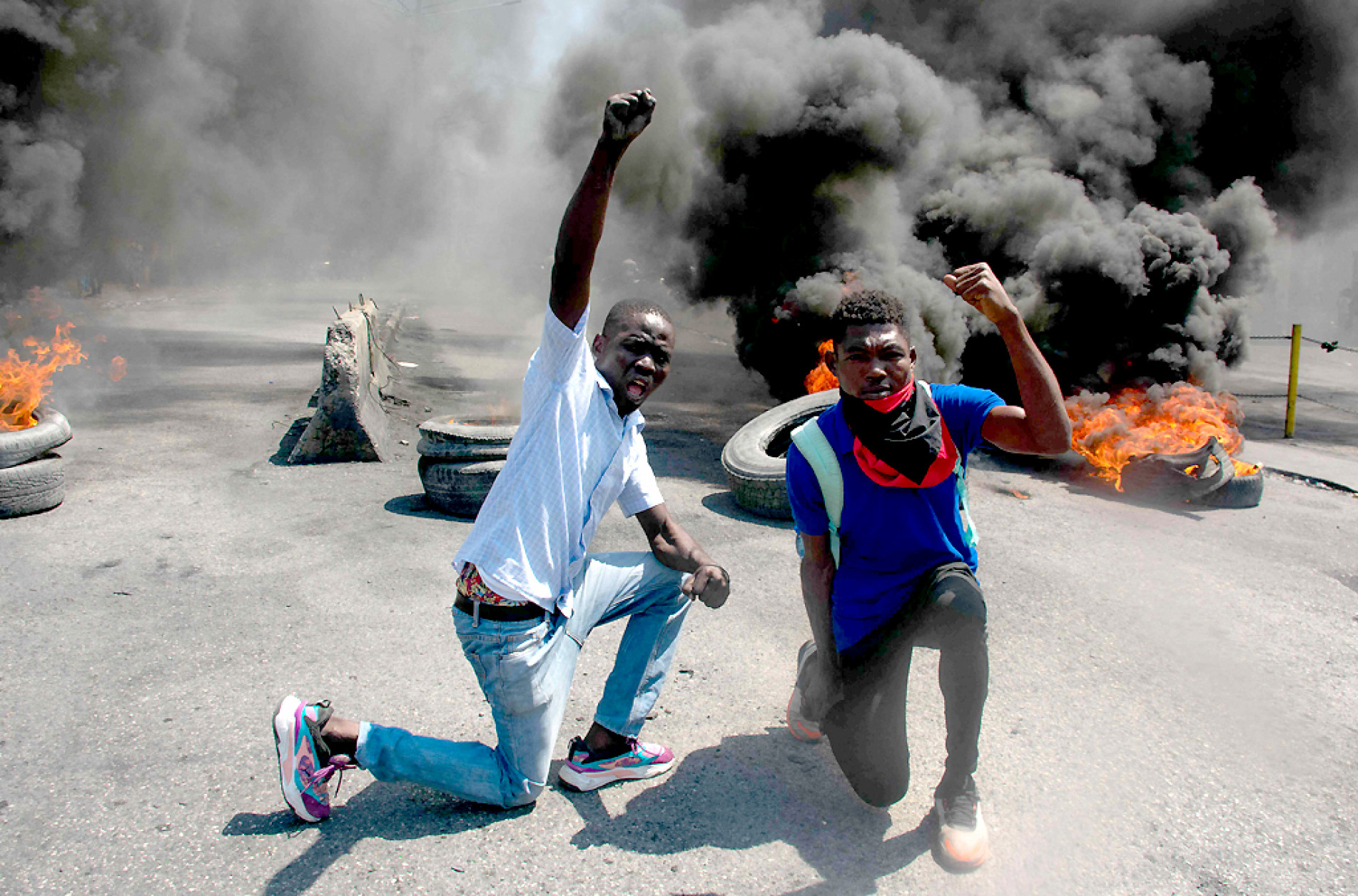 Manifestantes reagem enquanto pneus queimam nas ruas durante uma manifestação após a renúncia do primeiro-ministro Ariel Henry, em Porto Príncipe, Haiti