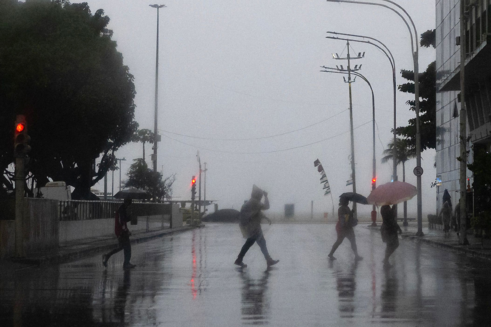 Pessoas atravessam uma rua em frente à praia de Copacabana, no Rio de Janeiro. 